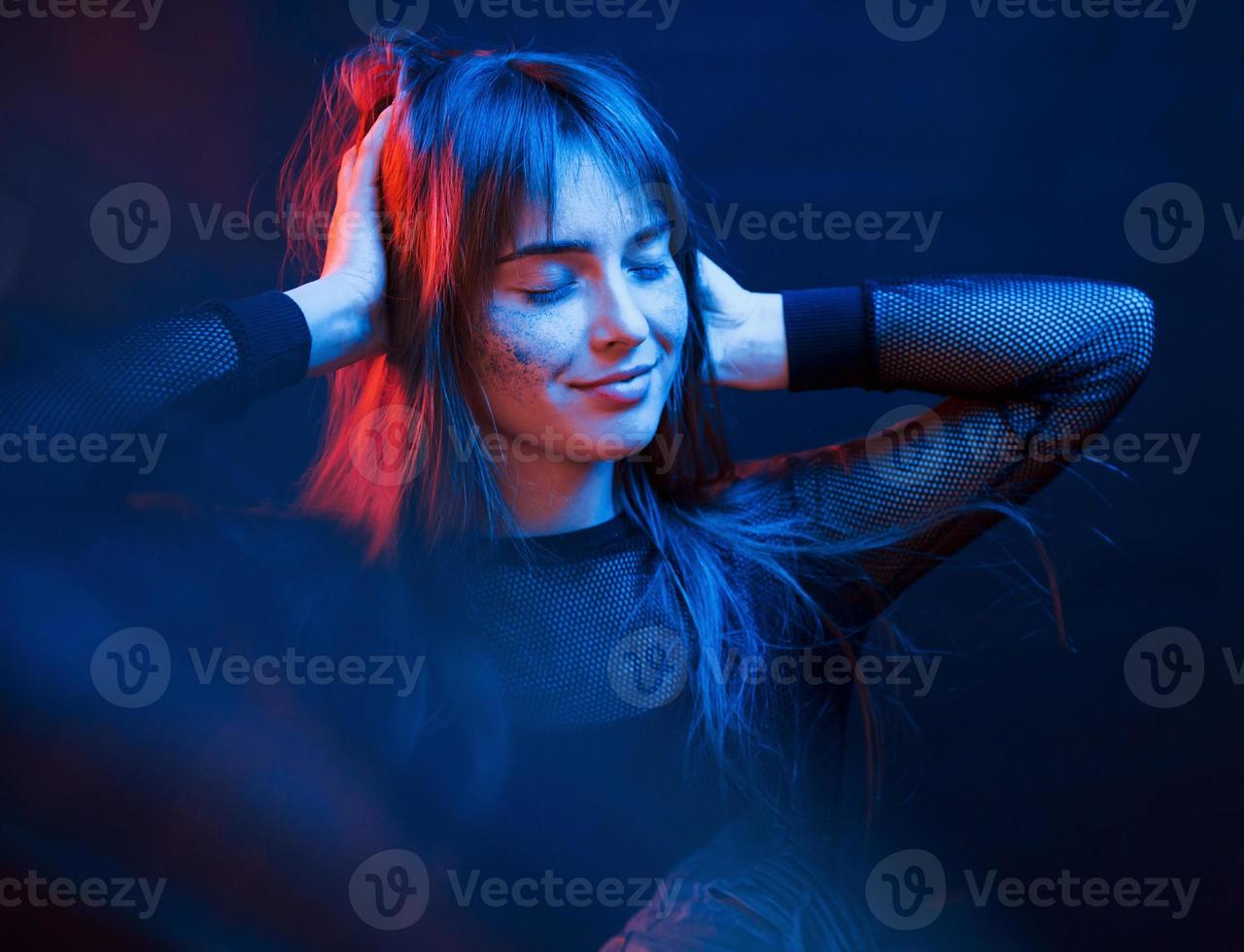 Standing in the lights. Studio shot in dark studio with neon. Portrait of young girl photo