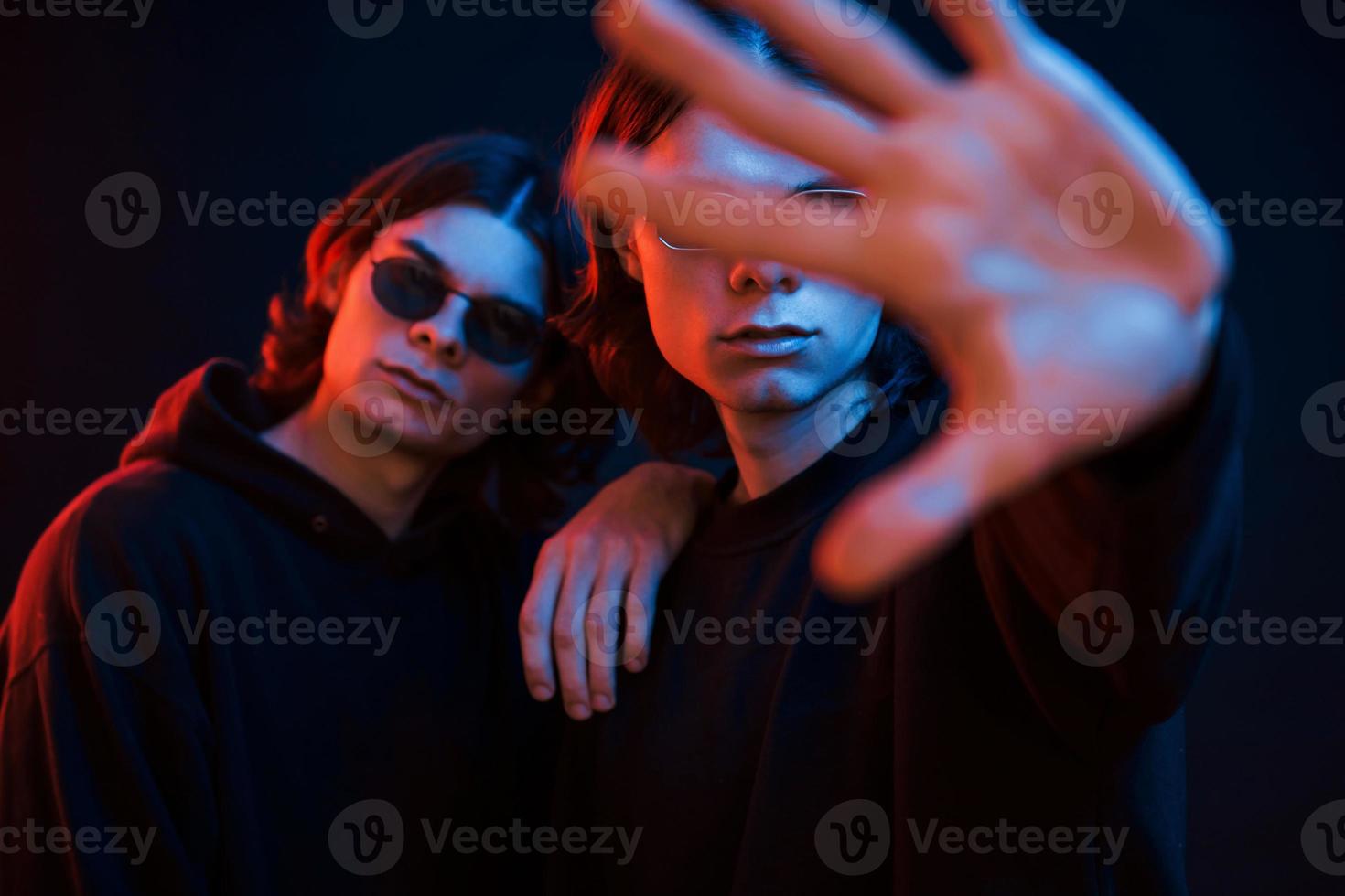 Stop gesture. Portrait of twin brothers. Studio shot in dark studio with neon light photo