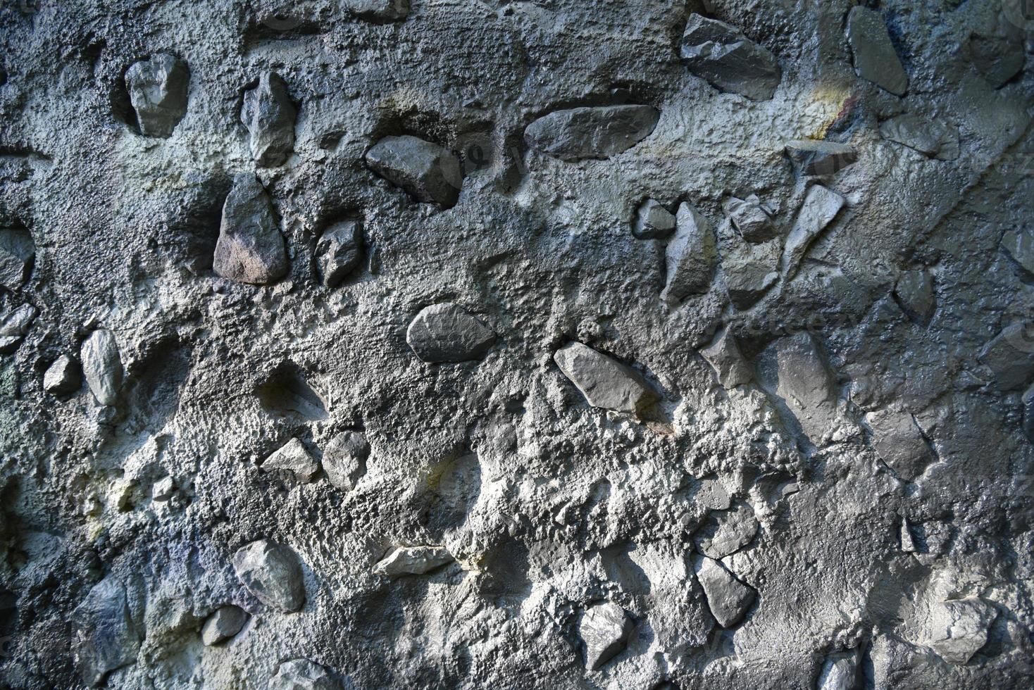 Grey painted concrete wall with stones in spots photo