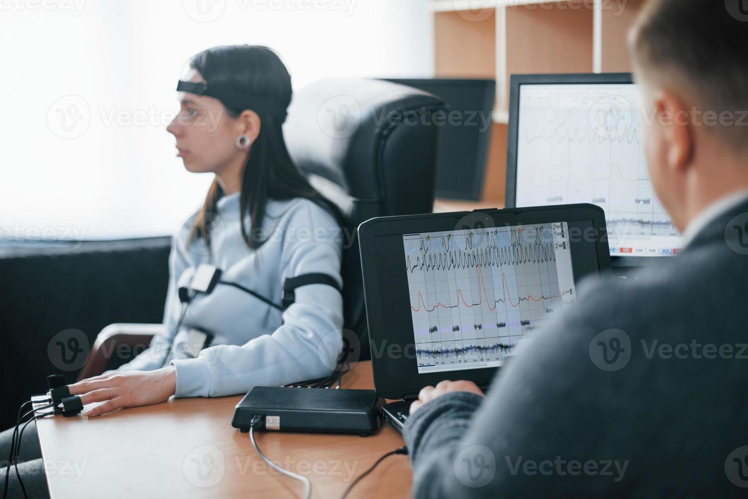 Girl passes lie detector in the office. Asking questions. Polygraph