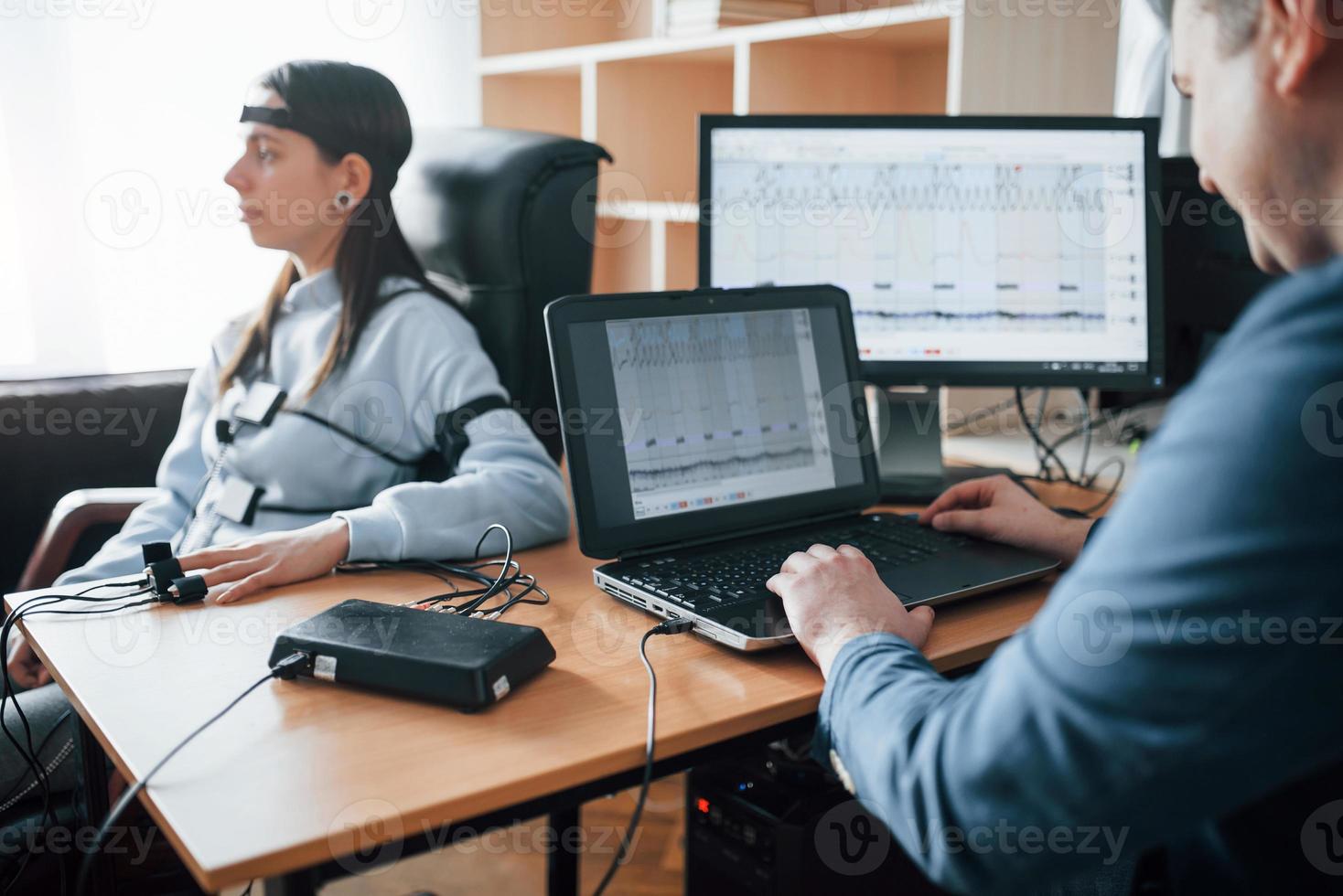 Checking the truth. Girl passes lie detector in the office. Asking questions. Polygraph test photo