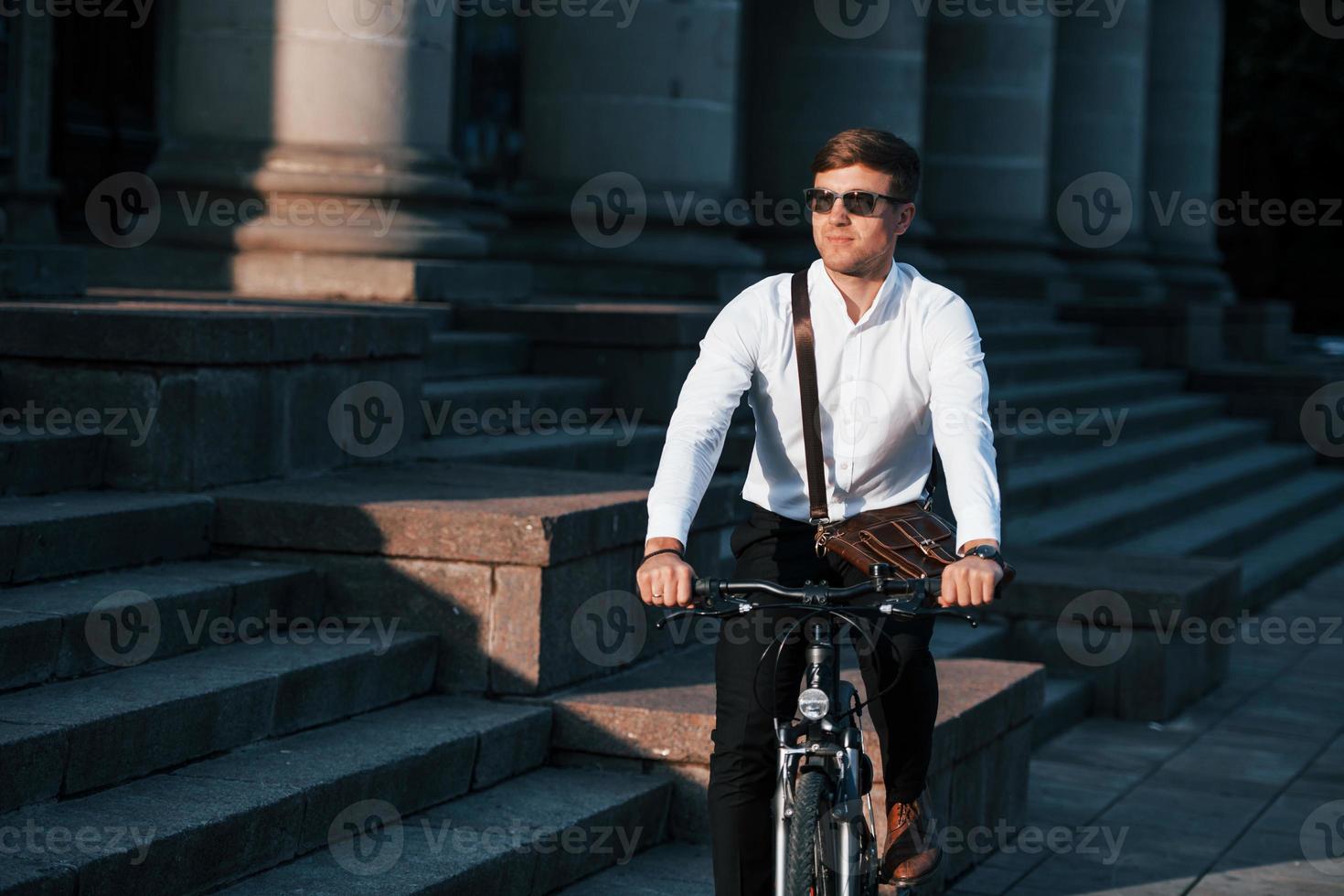 en gafas de sol. hombre de negocios en ropa formal con bicicleta negra está  en la ciudad 8569386 Foto de stock en Vecteezy