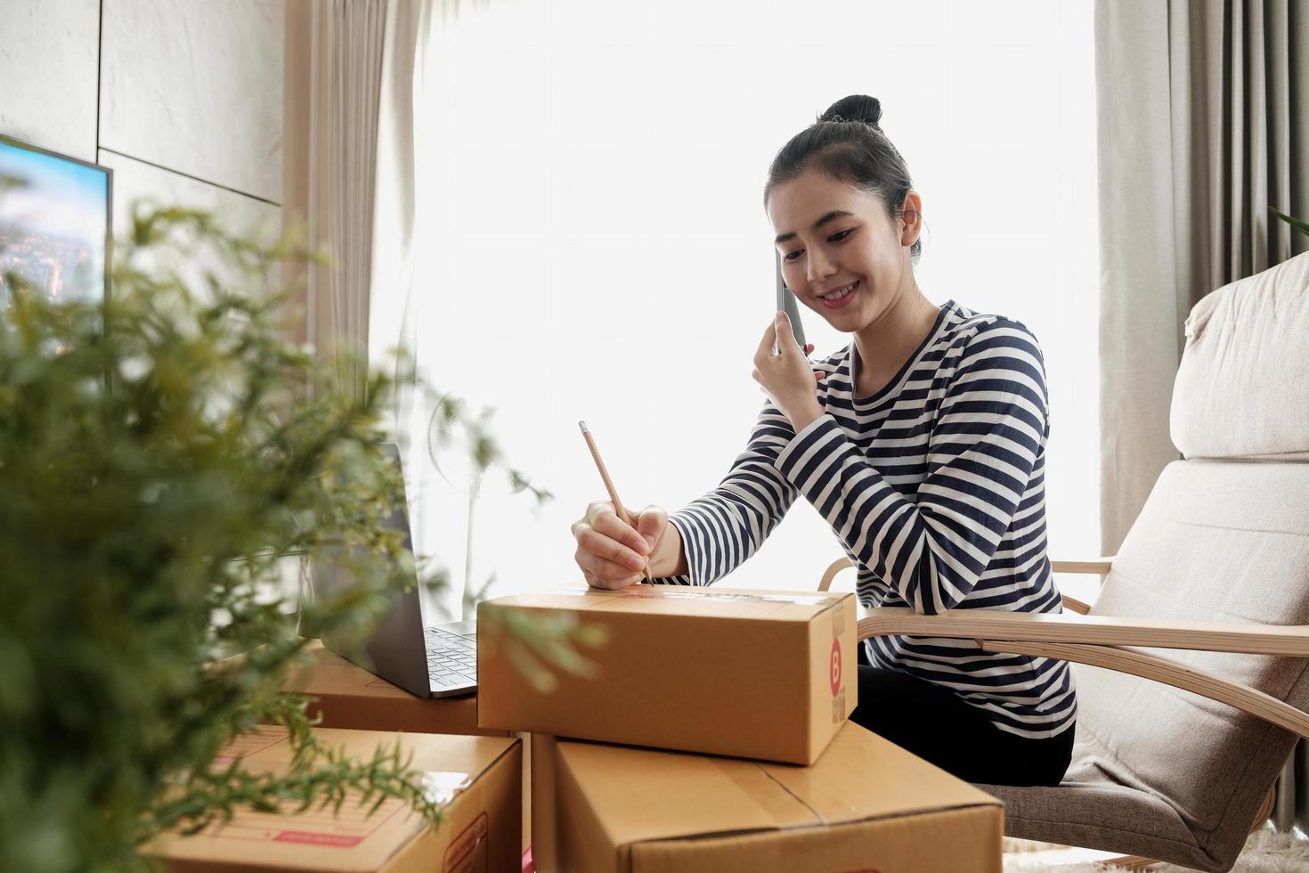 Business Start up SME concept. Young startup entrepreneur small business owner working at home, packaging and delivery situation. Women, owener of small business packing product in boxes photo