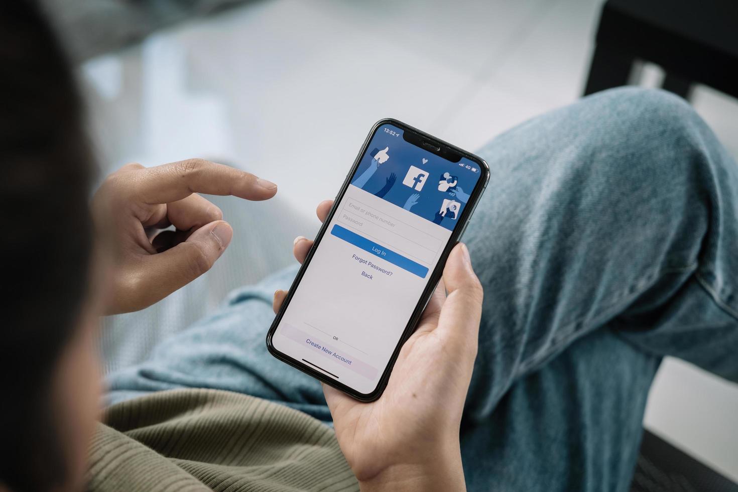 Facebook social media app logo on login signup registration page on mobile app screen on iPhone X 10 in person's hand working on ecommerce shopping business. photo