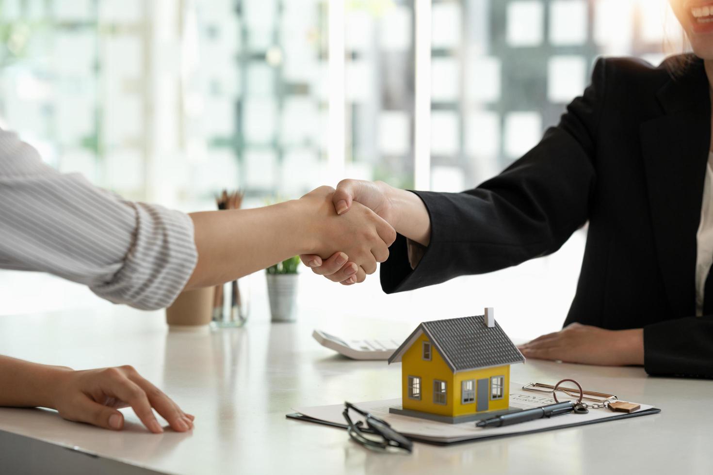 Real estate broker and customer shaking hands after signing a contract real estate, home loan and insurance concept photo