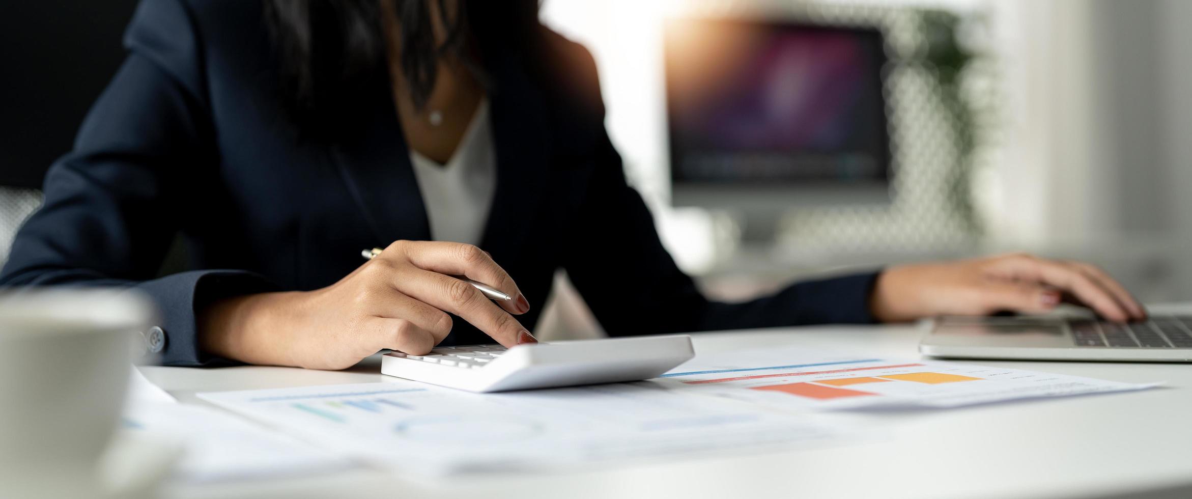 Businesswoman using calculator for analysis maketing plan, Accountant calculate financial report, computer with graph chart. Business, Finance and Accounting concepts photo