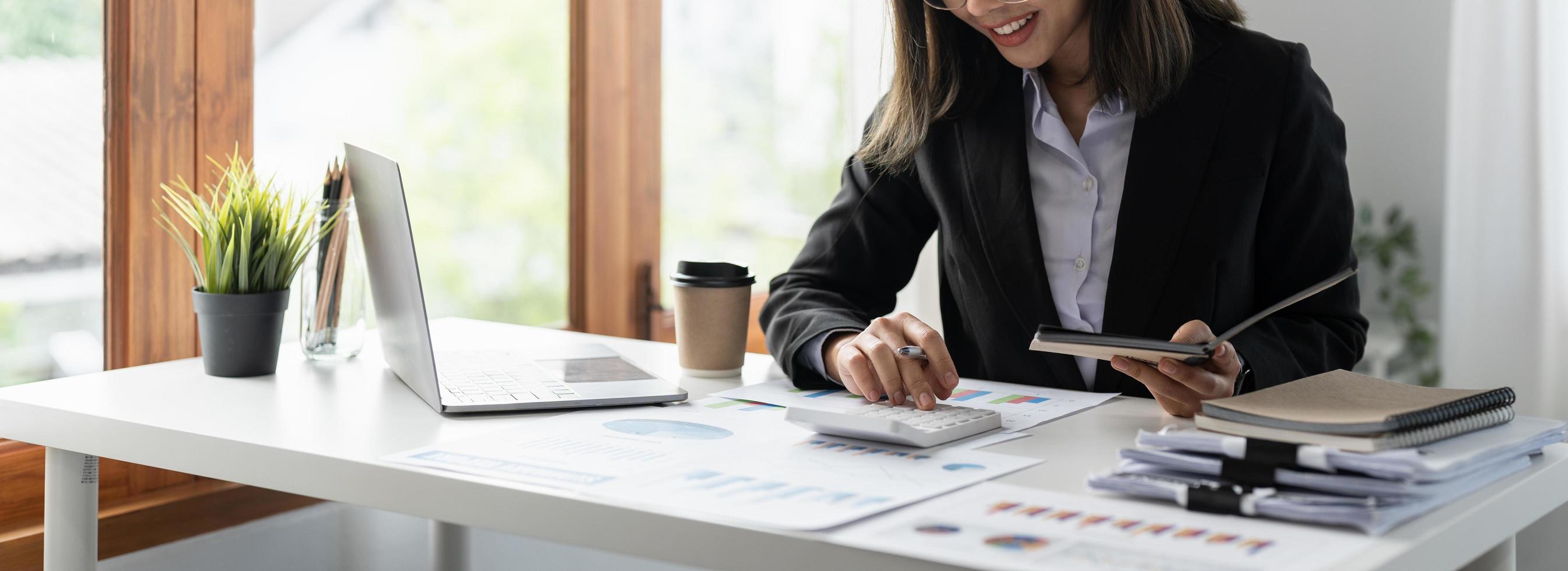 Businesswoman using calculator for analysis maketing plan, Accountant calculate financial report, computer with graph chart. Business, Finance and Accounting concept photo
