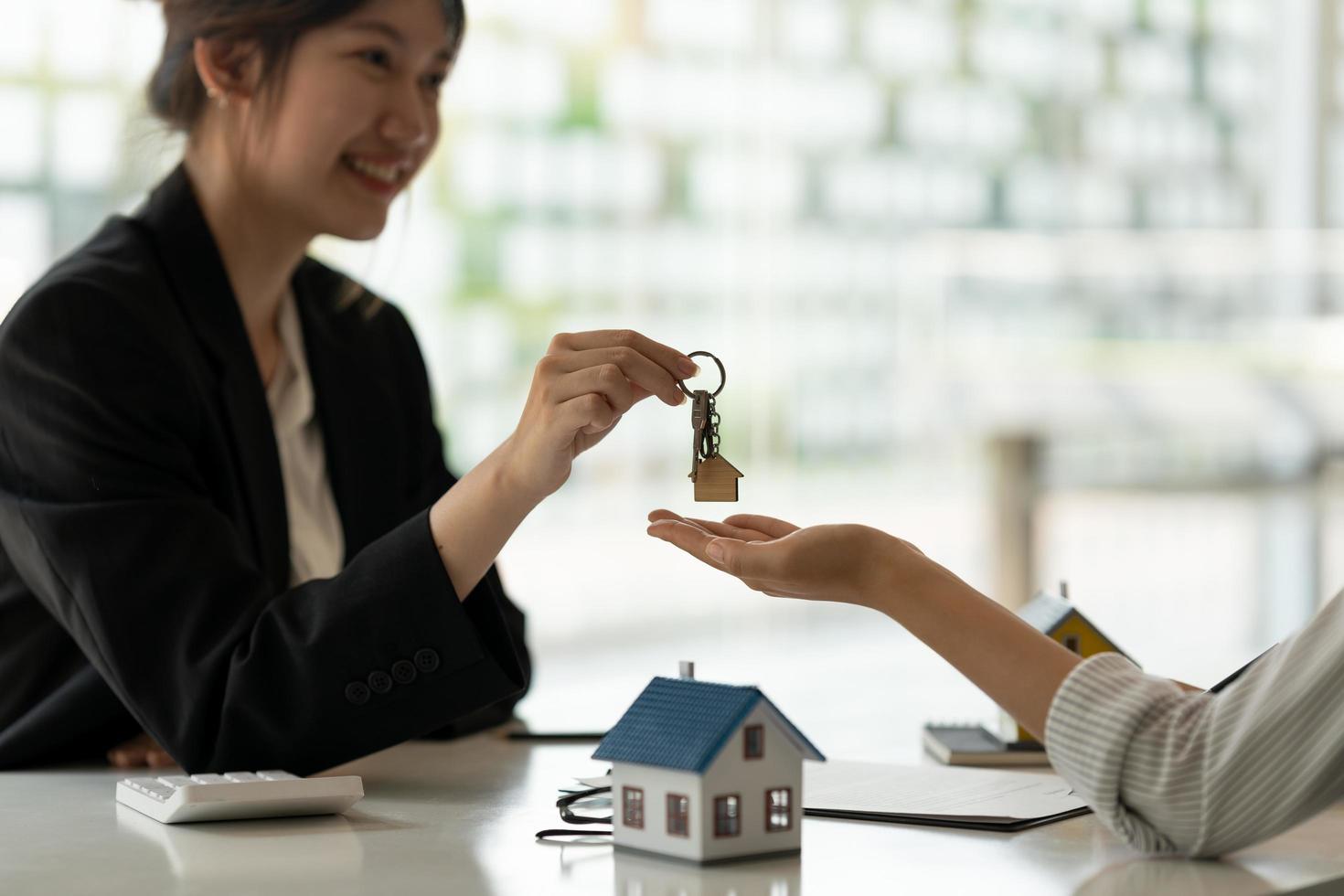 real estate agent holding house key to his client after signing contract agreement in office,concept for real estate, moving home or renting property photo