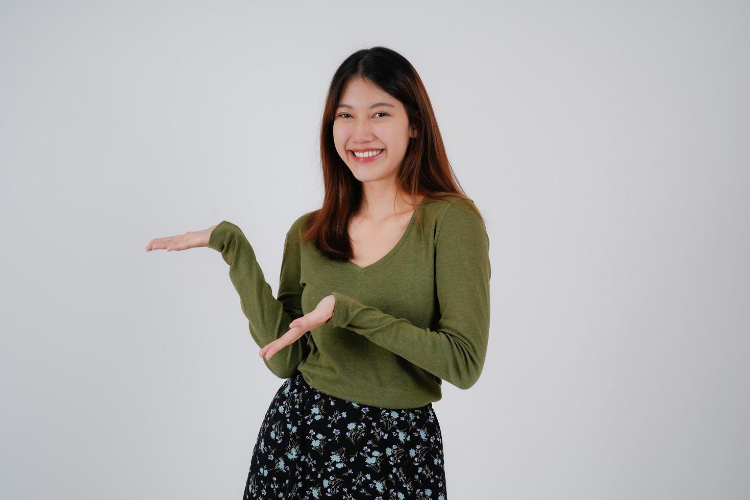 Young asian woman standing over isolated white background happy face smile looking at the camera. Positive person. photo