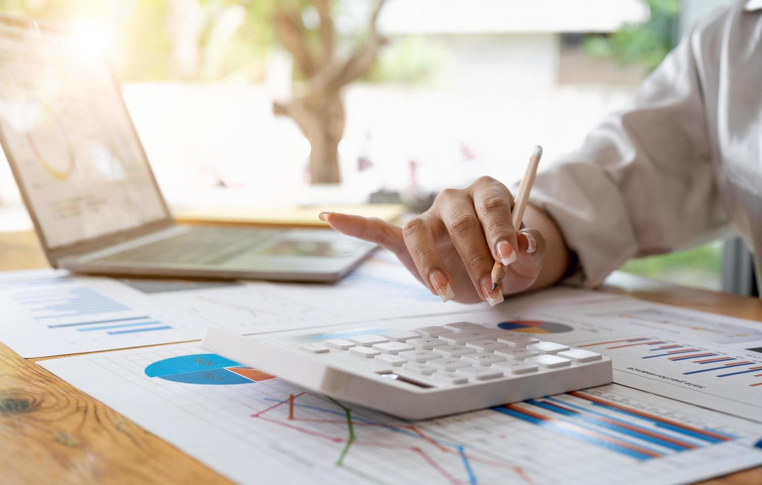 Close up of woman's hands. She is using her calculator and writing numbers down. Concept of accounting work. photo