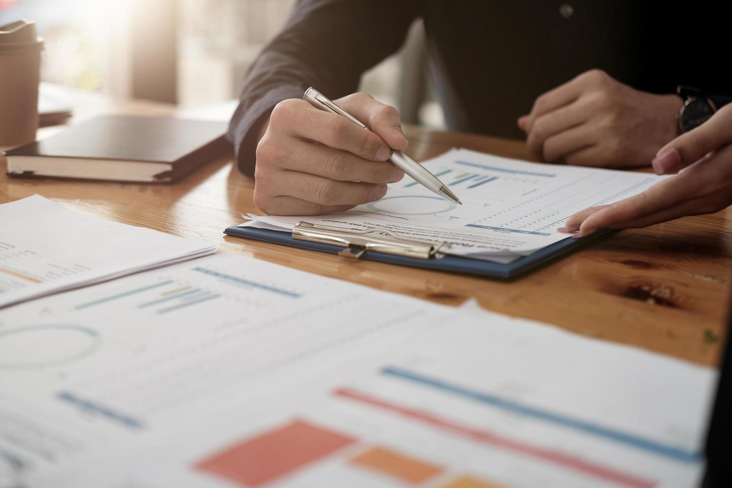 Close up  of businessman discussing analysis charts or graphs on desk table and using laptop computer. Close up male analysis and strategy concept. photo