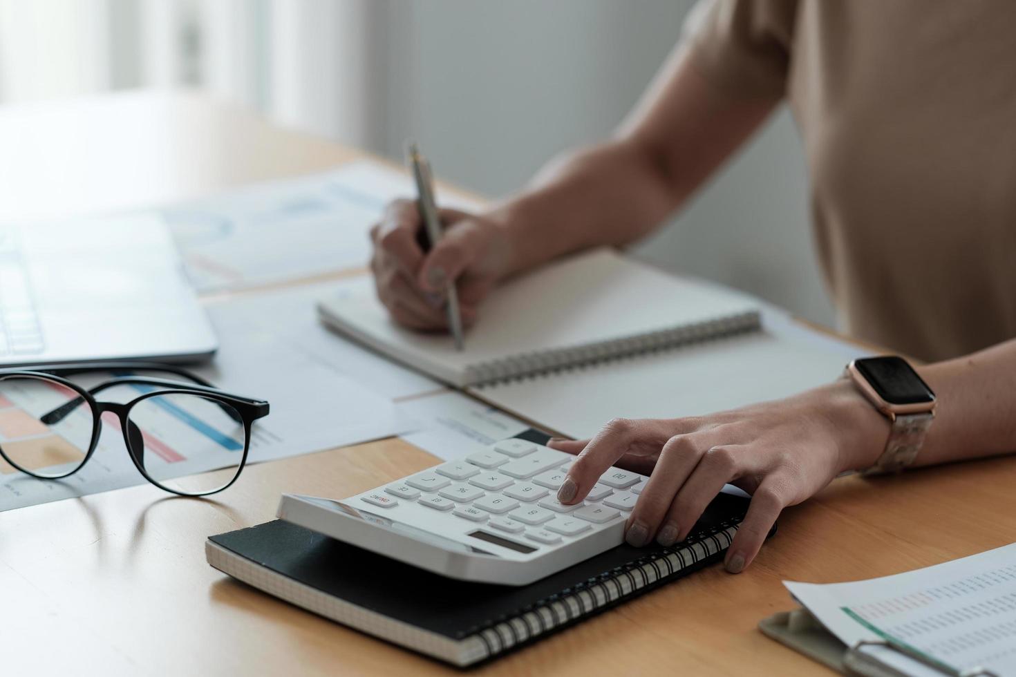 Close up hand of accounting is recording the company's financial growth statistics using graphs as a reference for reviewing and analyzing the results, Taking notes and analyzing data graphs in office photo