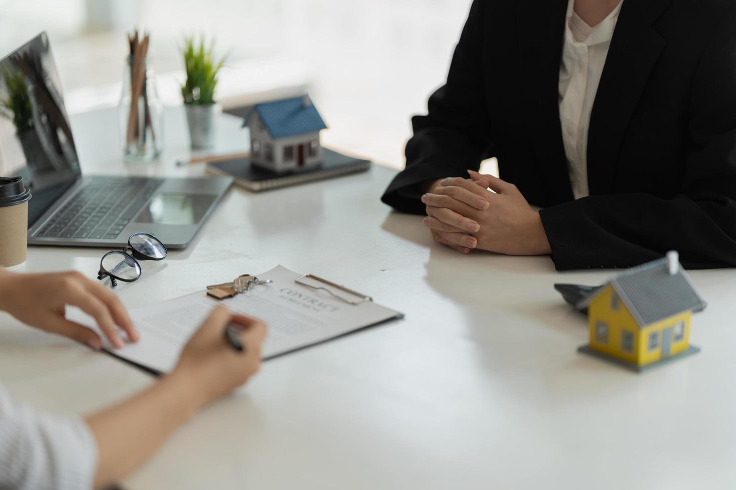 The real estate agent is explaining the house style to the clients who come to contact to see the house design and the purchase agreement photo