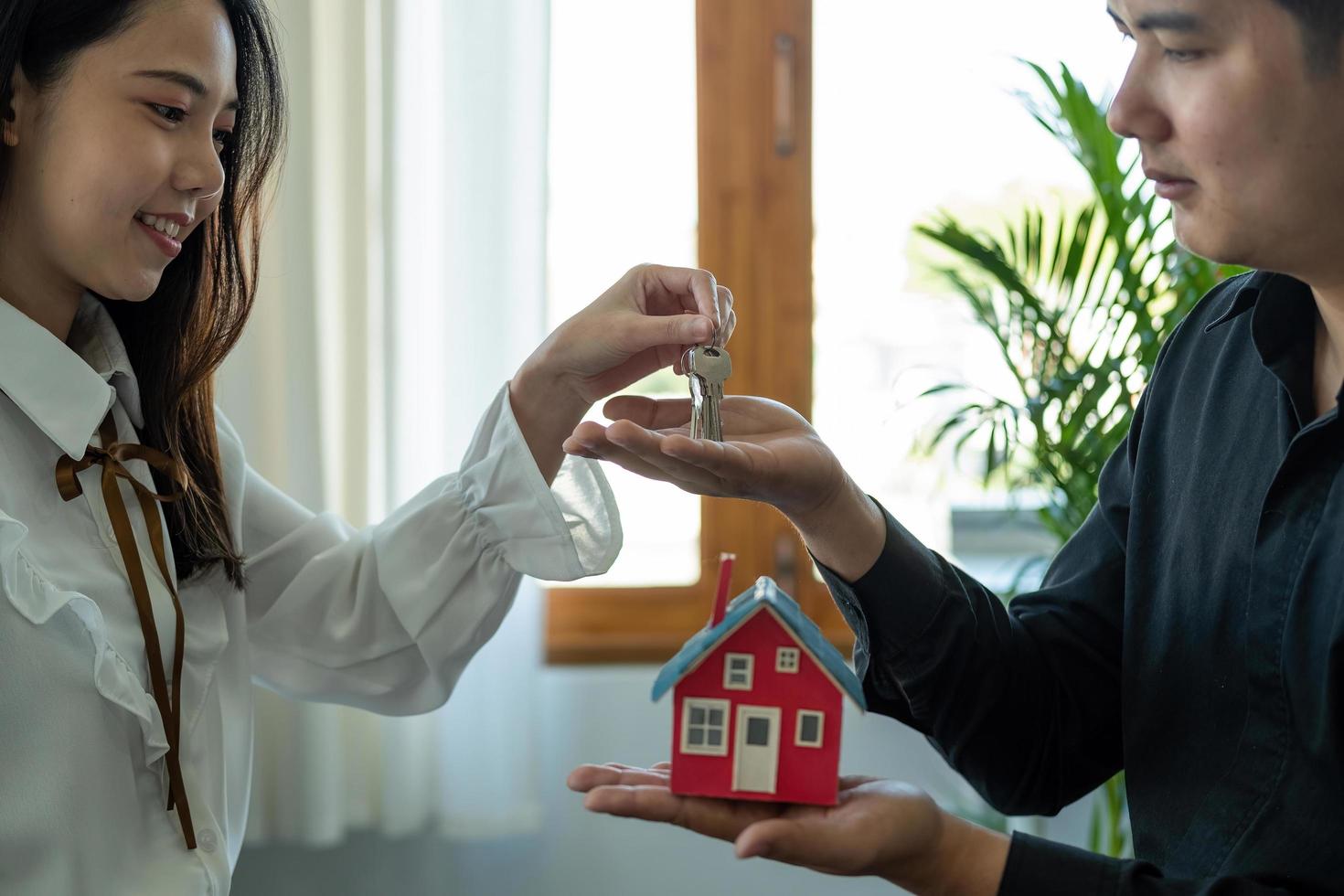 real estate agent holding house key to his client after signing contract agreement in office,concept for real estate, moving home or renting property photo