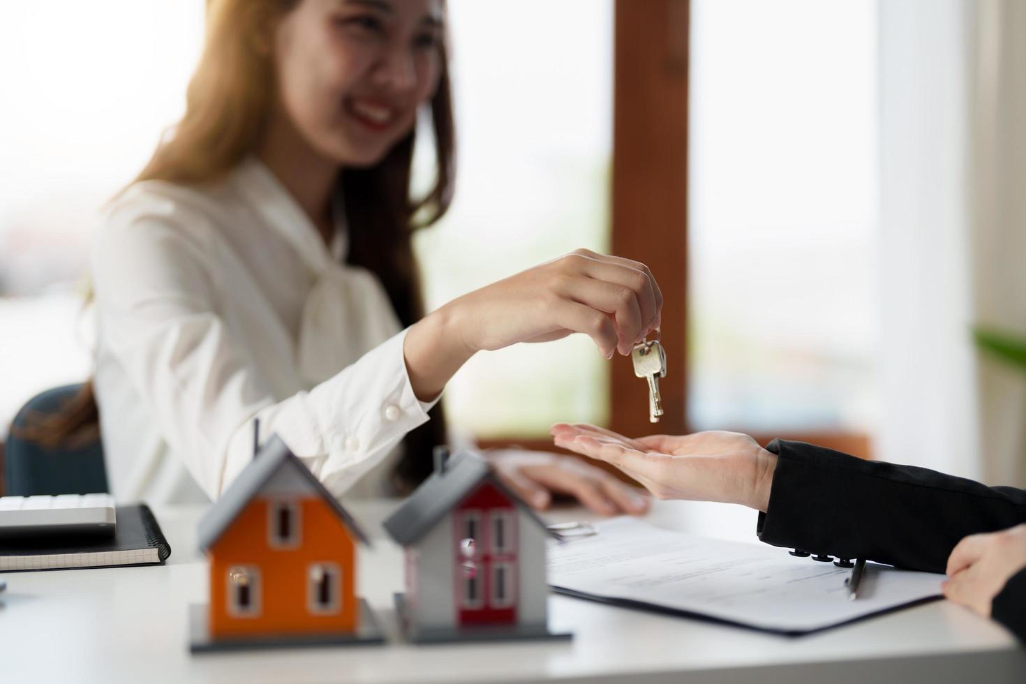 Real estate agent holding house key to his client after signing contract agreement in office,concept for real estate, moving home or renting property photo