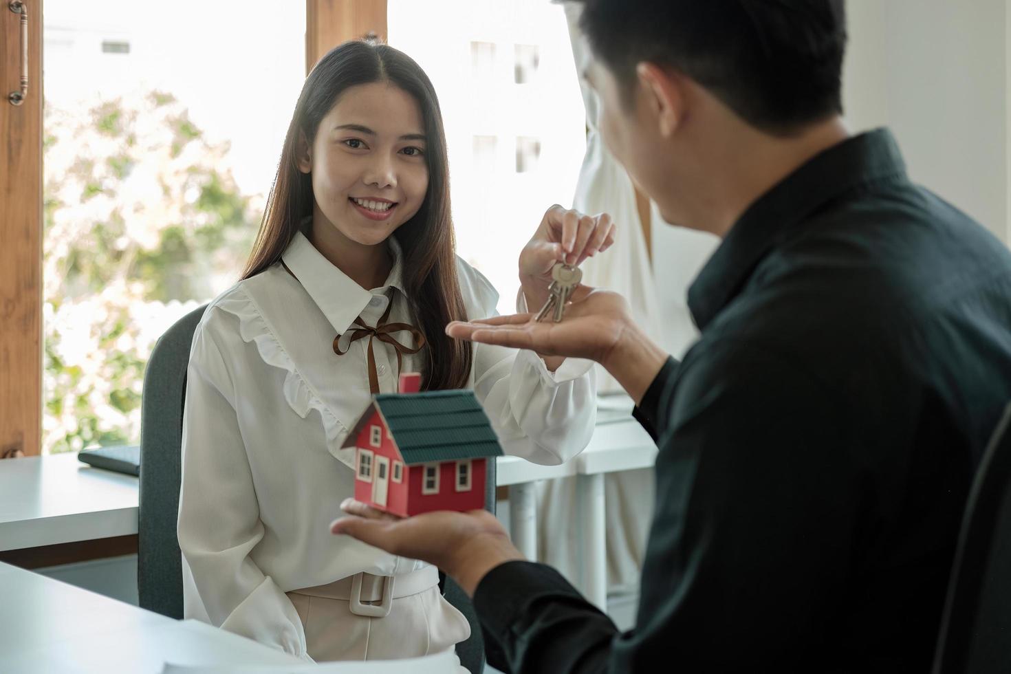 Agente de bienes raíces que tiene la llave de la casa para su cliente después de firmar un contrato en la oficina, concepto de bienes raíces, mudanza o alquiler de propiedad. foto