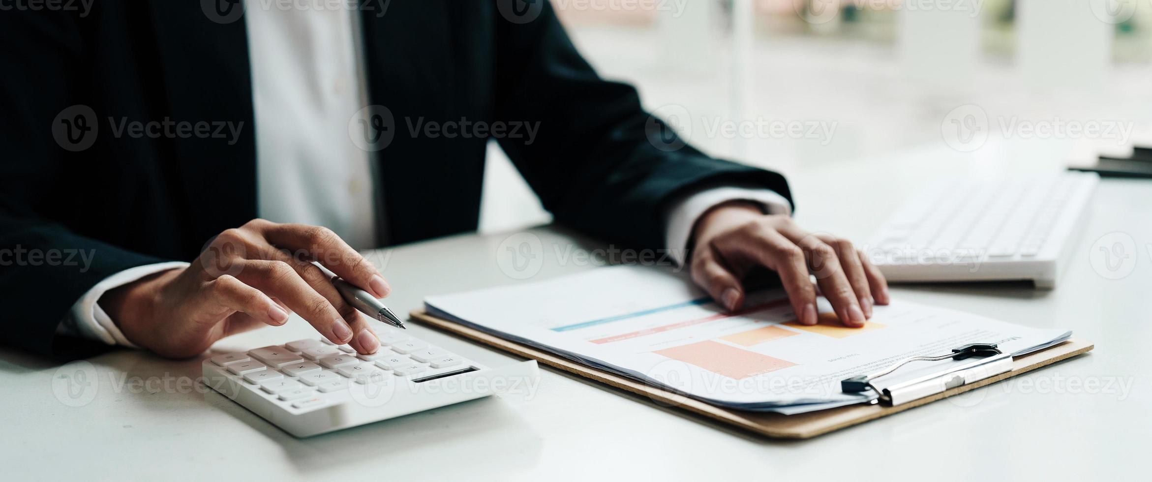 Close up accountant working on desk using calculator for calculate finance report in office. photo