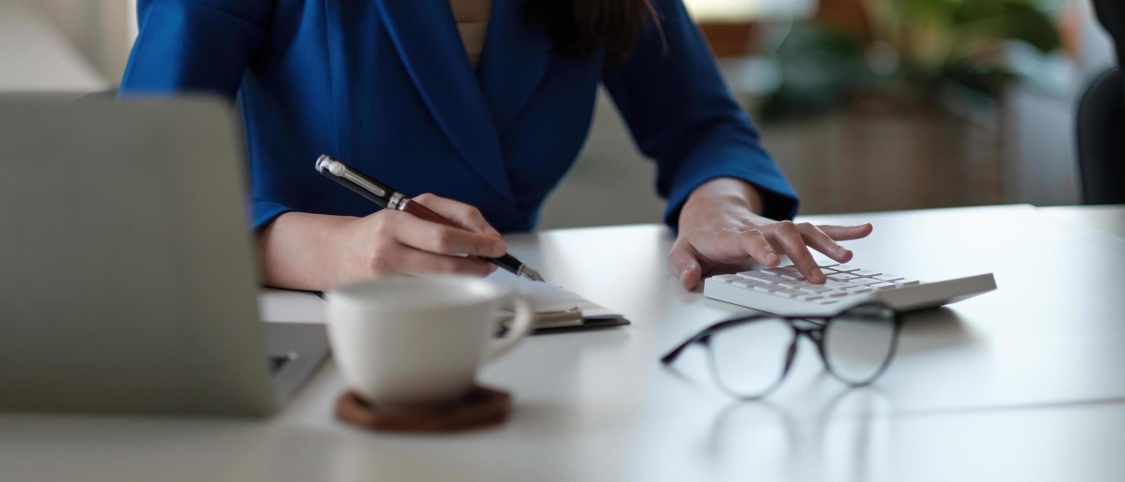 accounting is recording the company's financial growth statistics using calculator for reviewing and analyzing the results, Taking notes and analyzing data graphs in office. photo