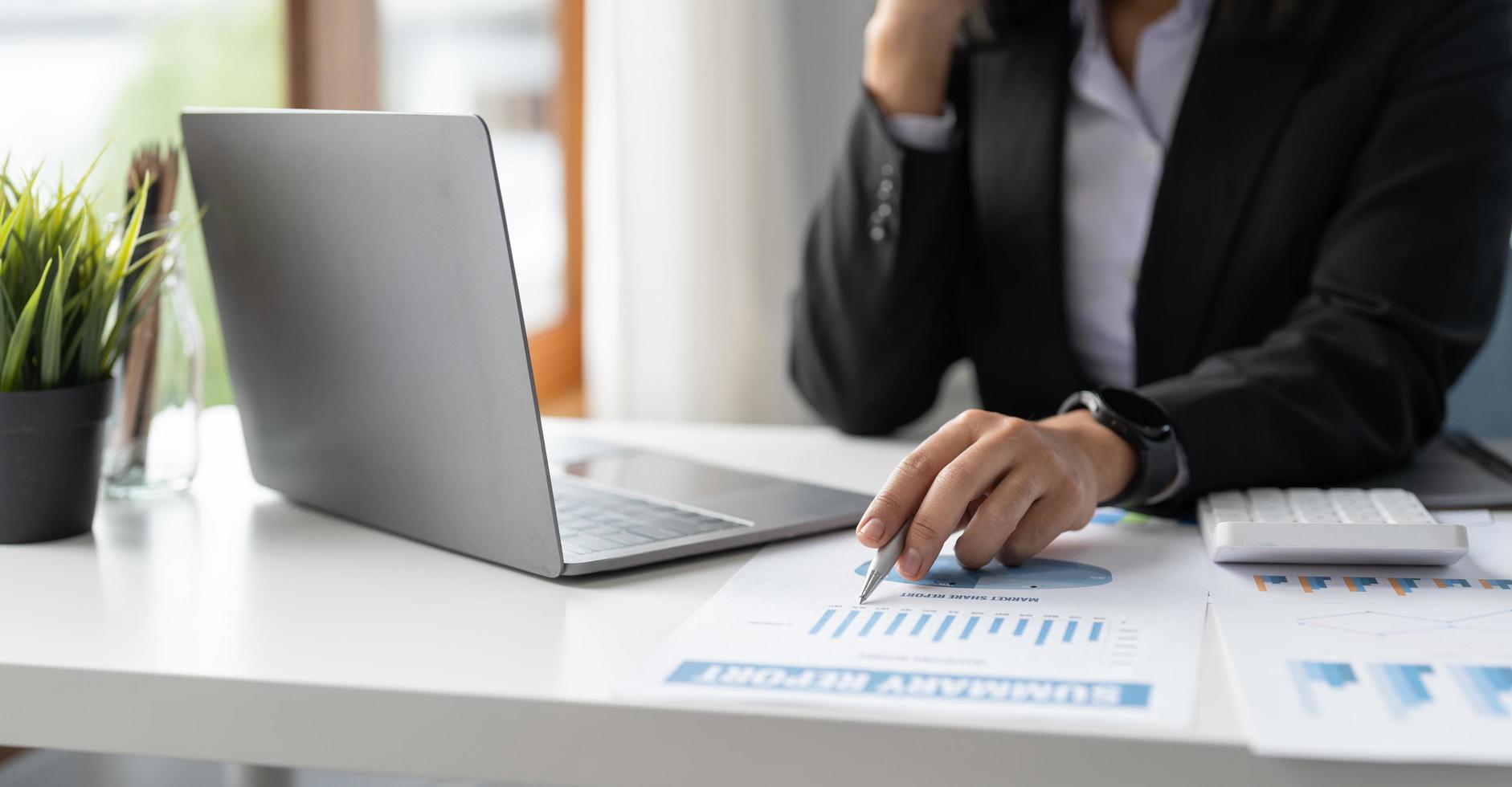 pluma de mujer de negocios o contadora que señala el volumen de negocios con un informe de gráfico y usa una computadora portátil para analizar datos foto