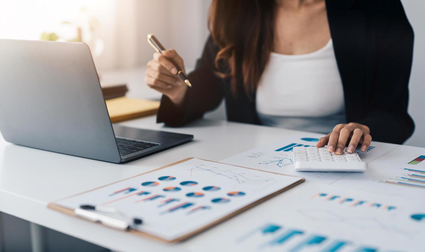 Close up asian woman planning budget, using calculator and laptop, reading documents, young female checking finances, counting bills or taxes, online banking services, sitting at desk photo