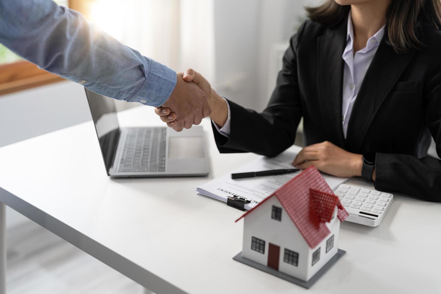 agentes inmobiliarios y clientes se dan la mano para felicitar por firmar un contrato para comprar una casa con tierra y seguro, apretón de manos y concepto de buena respuesta foto