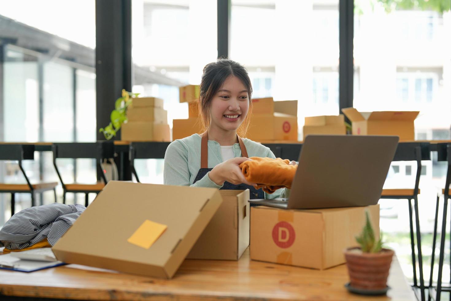 young start up small business owner packing cardboard box at workplace. freelance woman seller prepare parcel box of product for deliver to customer. Online selling, e-commerce, shipping concept photo