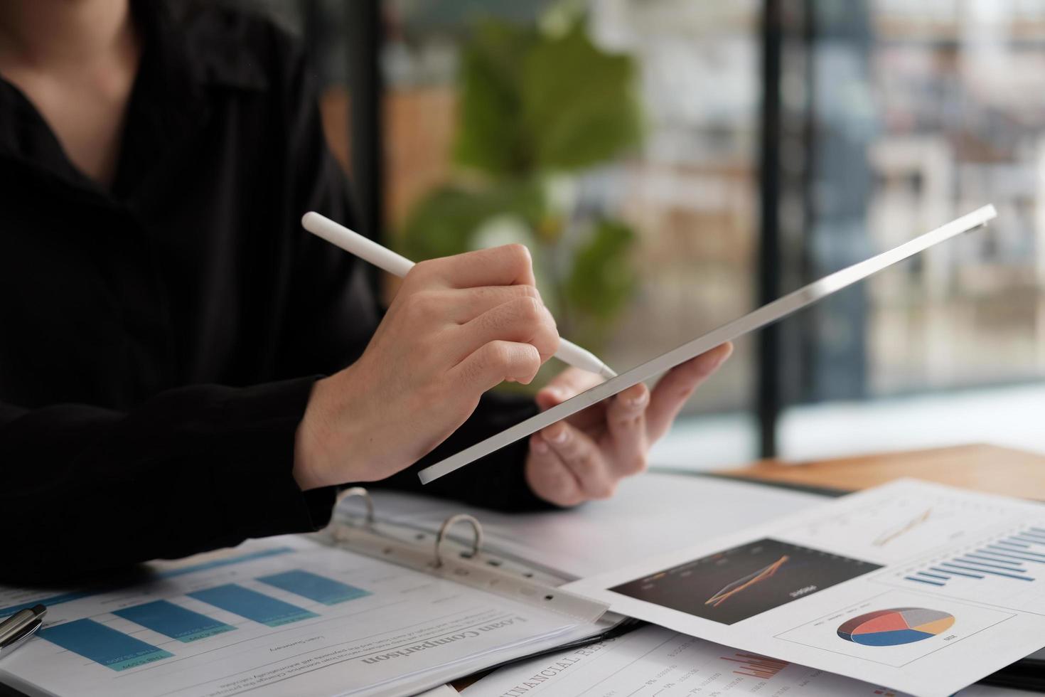 cerrar la mano de una mujer de negocios usando un lápiz óptico con una tableta digital para la contabilidad financiera a partir del gráfico de papeleo foto