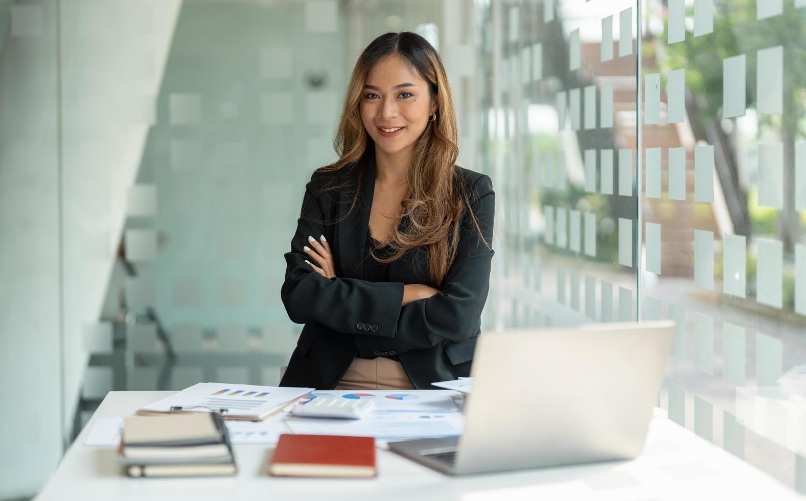 Portrait asian business woman with crossed arms looking at the camera working with laptop computer for accounting financial at office. photo