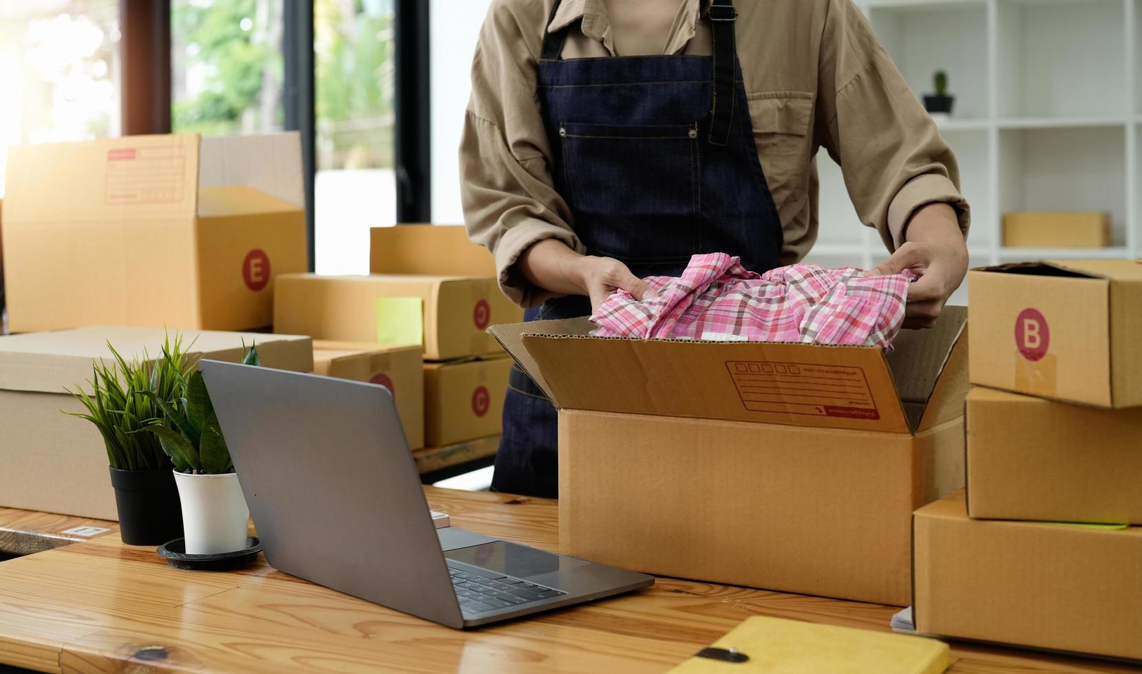 Close up young businessman owner packing clothes to cardboard box, Young Owner Woman Start up for Business Online. People with online shopping SME entrepreneur or freelance working concept. photo