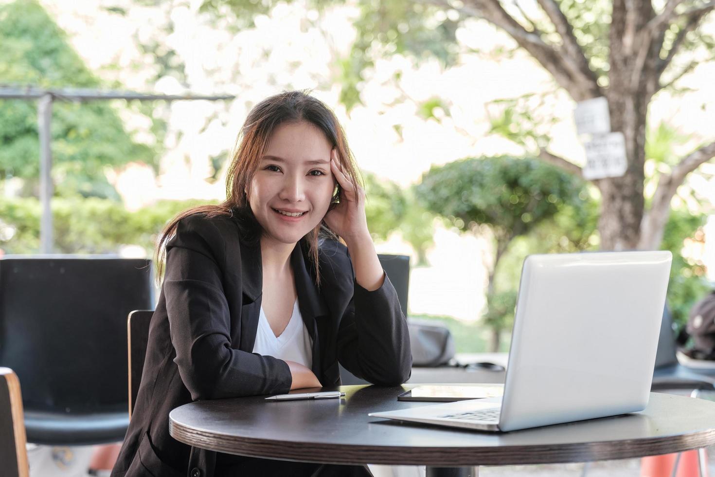 Portrait charming asian businesswoman sitting working on laptop in office. looking on camera photo