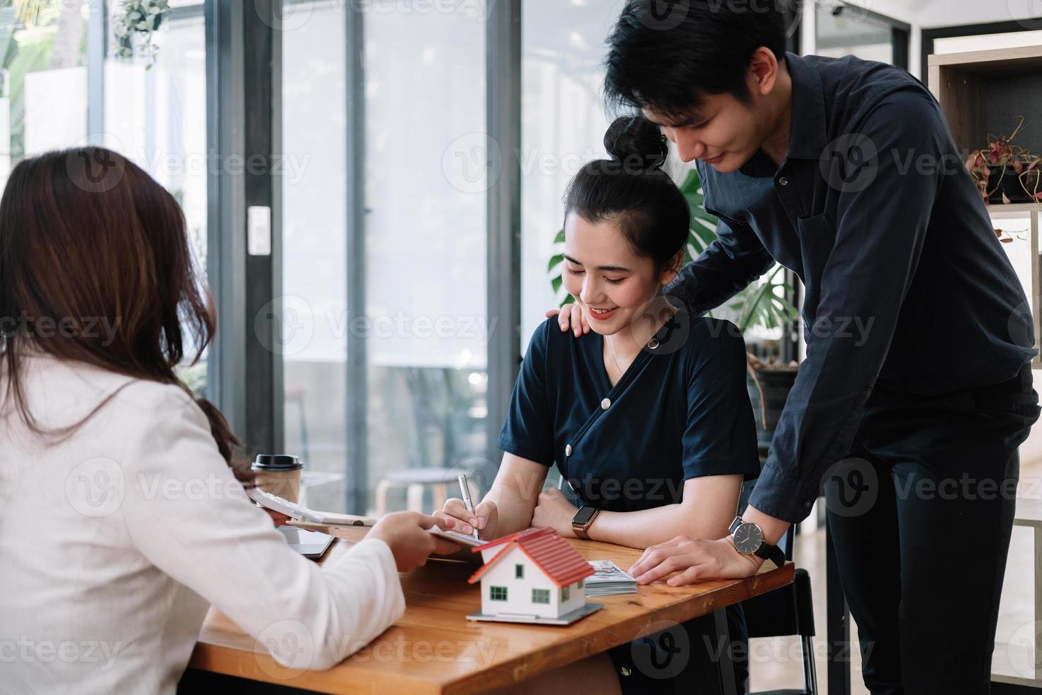 Real estate agent offer hand for customer sign agreement contract signature for buy or sell house. Happy asian couple signing a contract together at office. Real estate concept contact photo