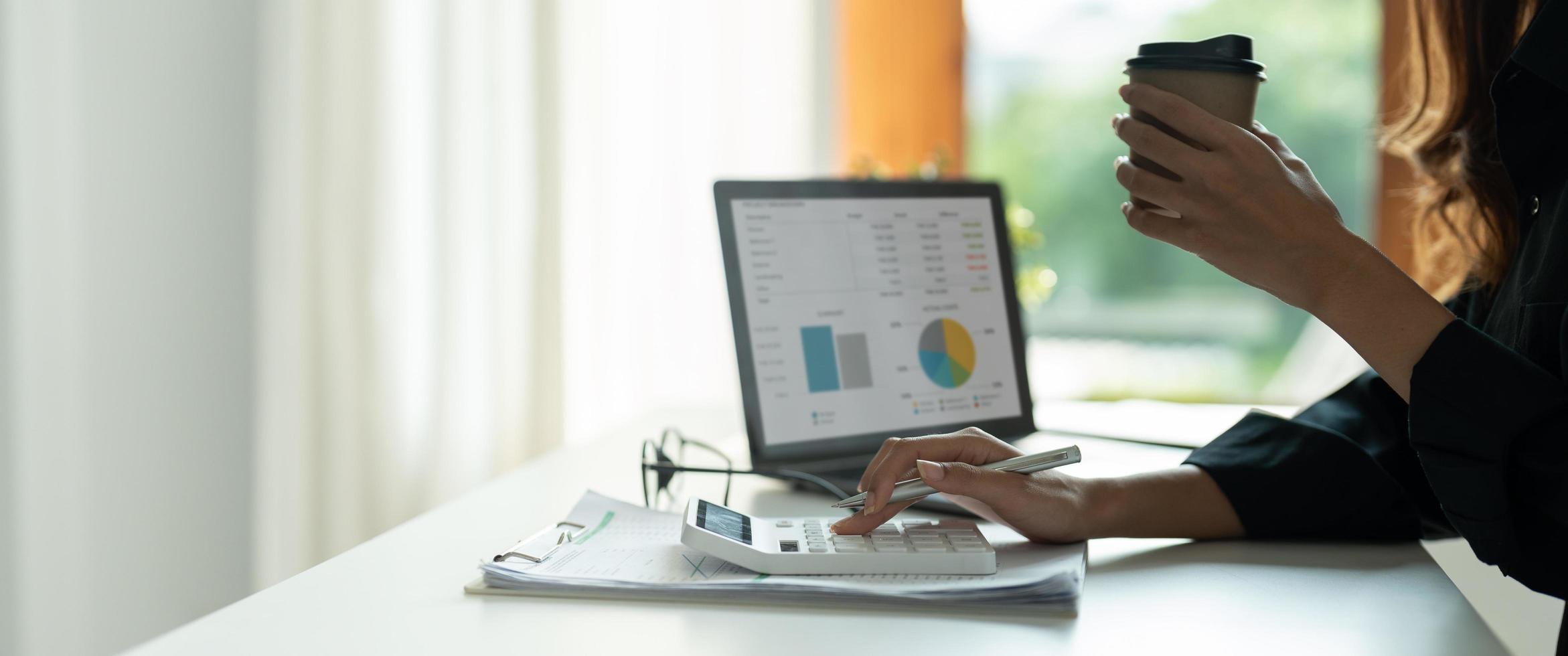 Close up hand of woman planning budget, using calculator, reading documents, young female checking finances, counting bills or taxes, online banking services, sitting at desk photo