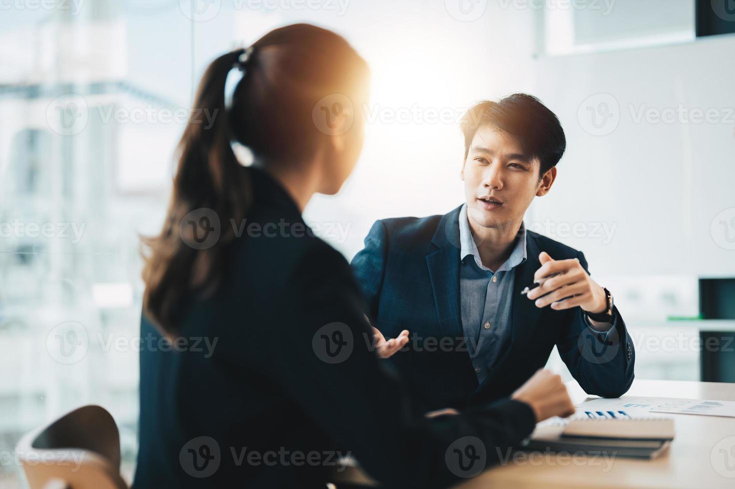 Two diverse asian business people discussing work together in an office photo