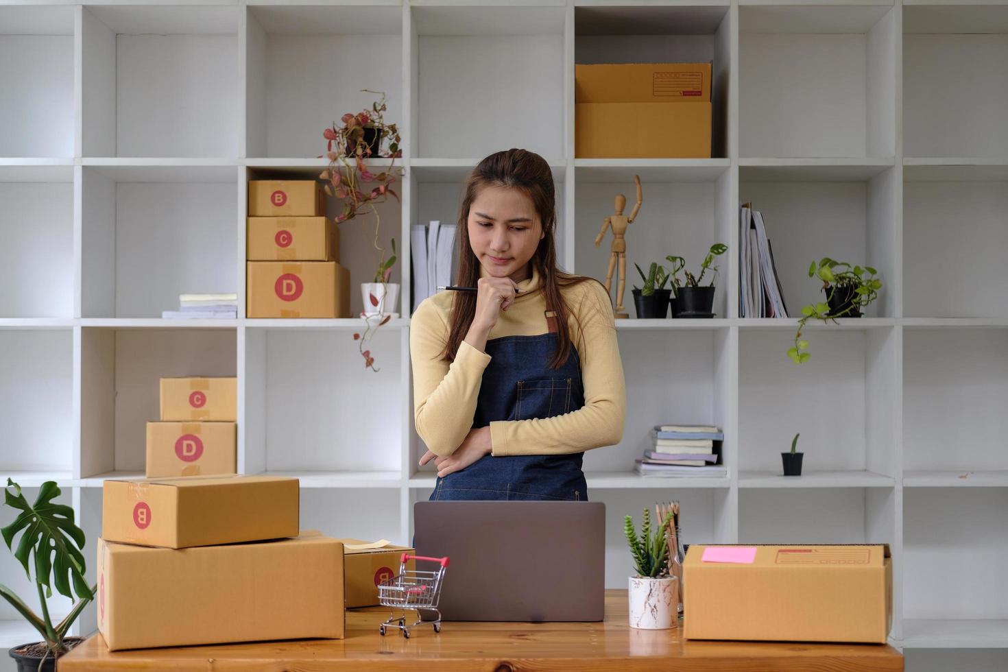 Start up small business entrepreneur SME or freelance asian woman using laptop with box, Young success Asian woman with her hand lift up , online marketing packaging box and delivery, SME concept photo