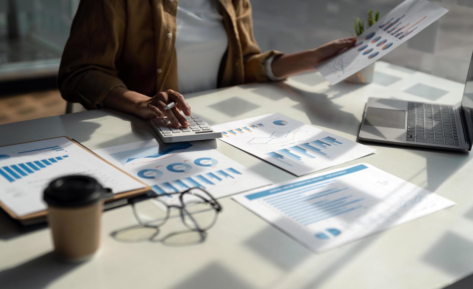 Close up accountant woman using calculator and laptop for do math finance on wooden desk in office and business working background, tax, accounting, statistics and analytic research concept photo