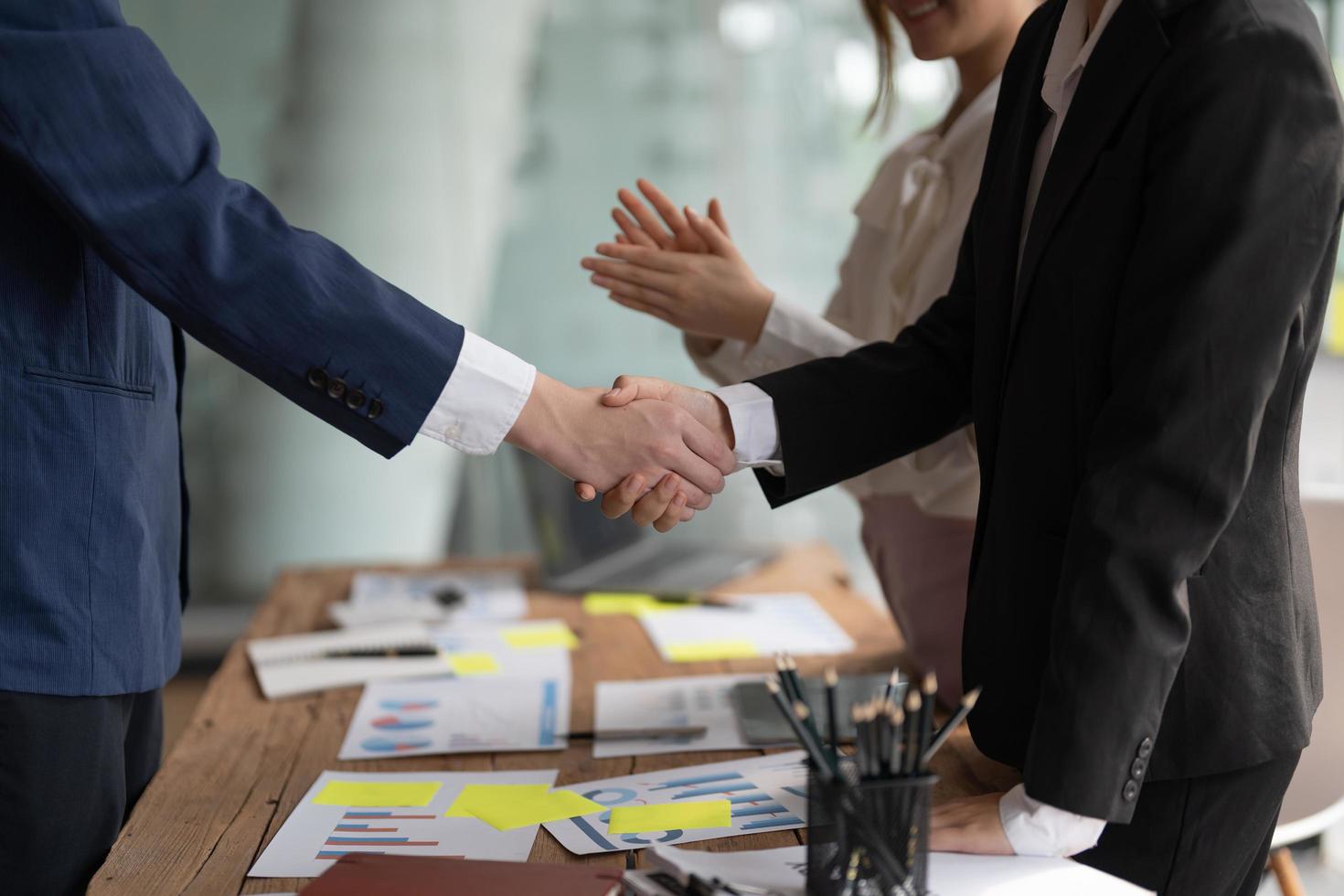 Group business people handshake at meeting table in office together with confident shot from top view . Young businessman and businesswoman workers express agreement of investment deal photo