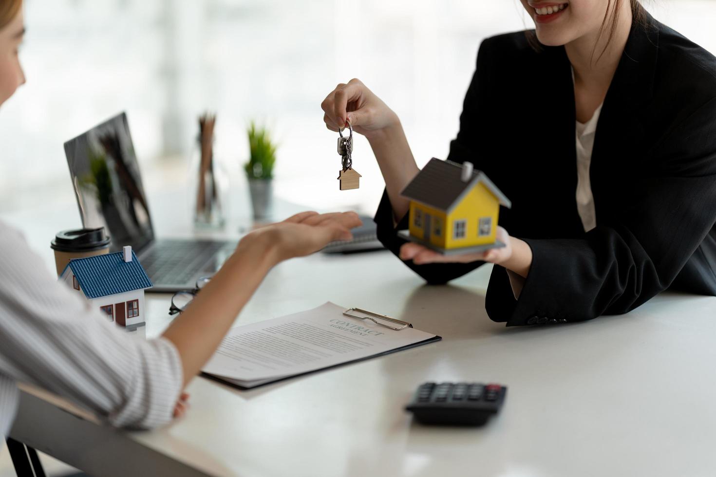 Agente de bienes raíces que tiene la llave de la casa para su cliente después de firmar un contrato en la oficina, concepto de bienes raíces, mudanza o alquiler de propiedad. foto