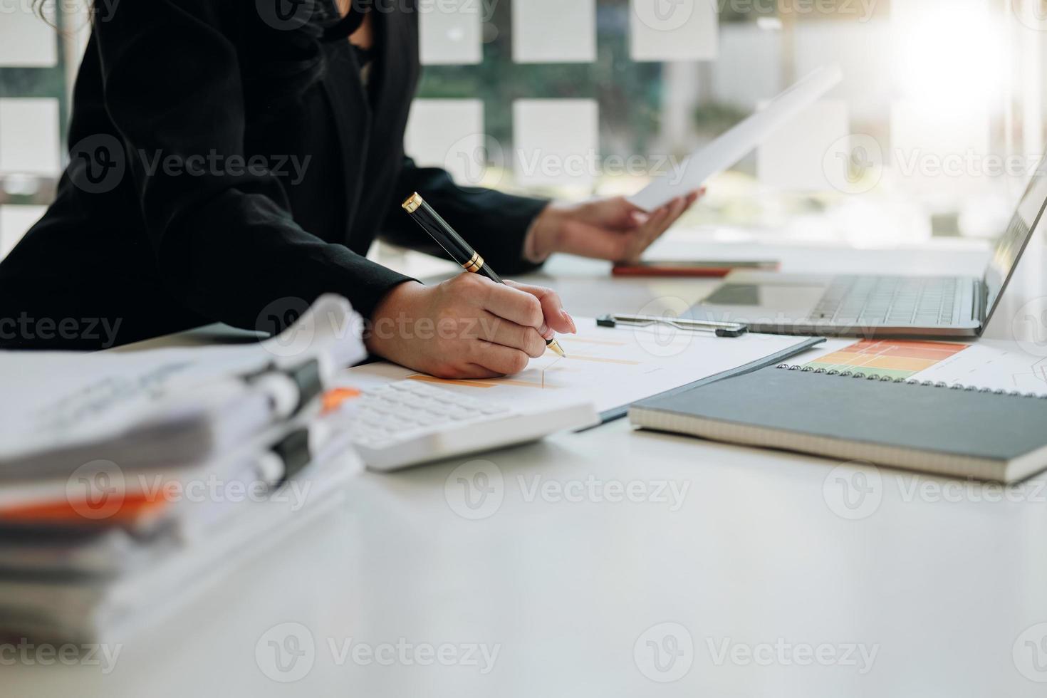 Close up of businesswoman holding a pen and pointing at the information sheet on his desk, reading the company's financials to make a financial plan. Financial concept. photo