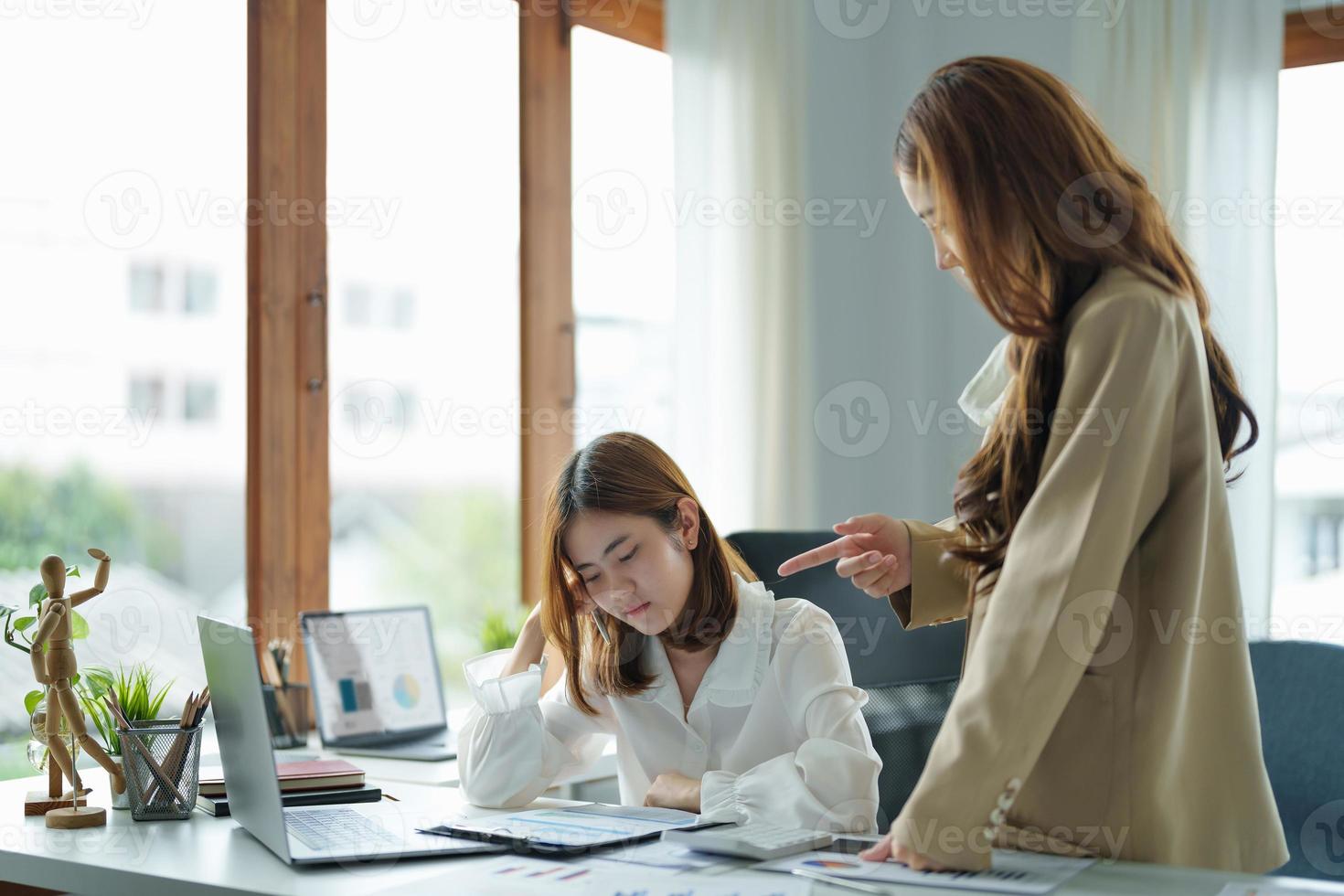 Young business woman feeling be serious, holding her head while her boss is complaining about the work. photo