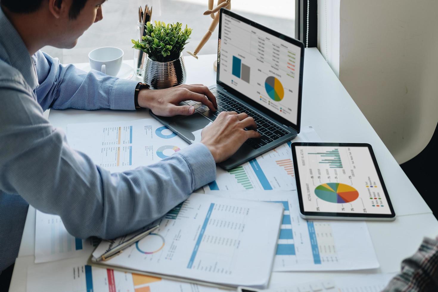 Businessman working and analyzing financial report on laptop with calculate statistics of financial document data graph for new project of business strategy and market growth at workplace photo