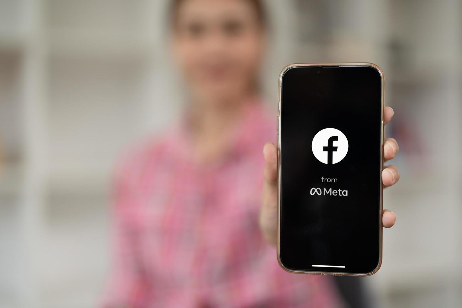 logotipo de la aplicación de medios sociales de facebook en la pantalla de la aplicación móvil en el iphone 13 en la mano de una persona que trabaja en negocios de compras de comercio electrónico foto