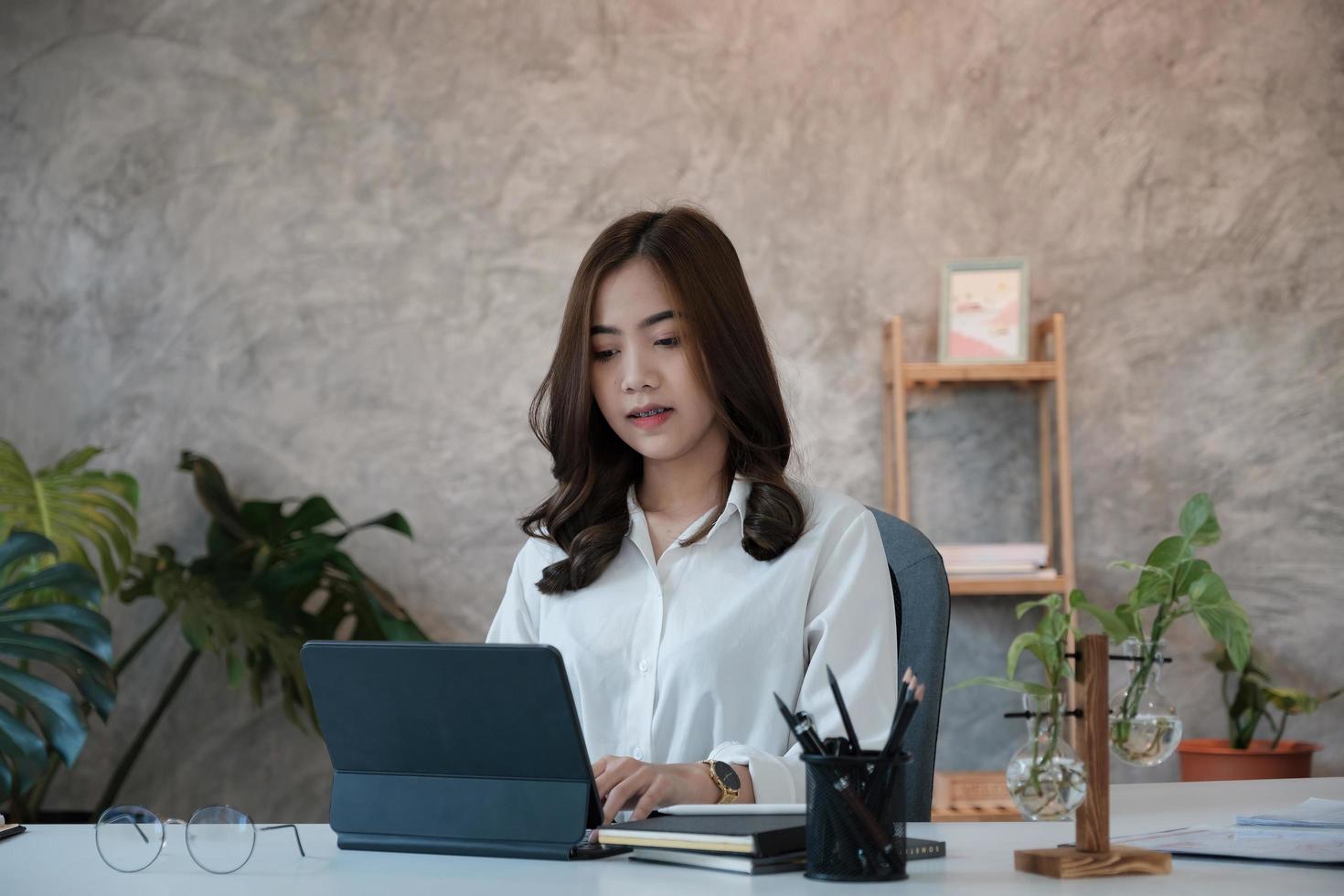 Thinking about business. Thoughtful young woman looking at digital tablet screen while sitting at his working place at home. Working remotely photo