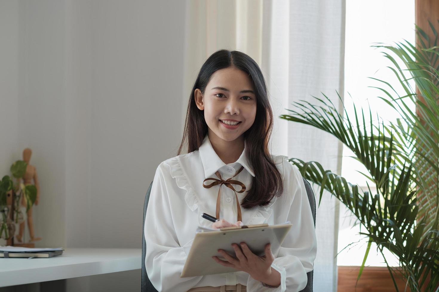 Portrait of beautiful asian businesswoman looking on camera while working with paperwork at modern office. photo