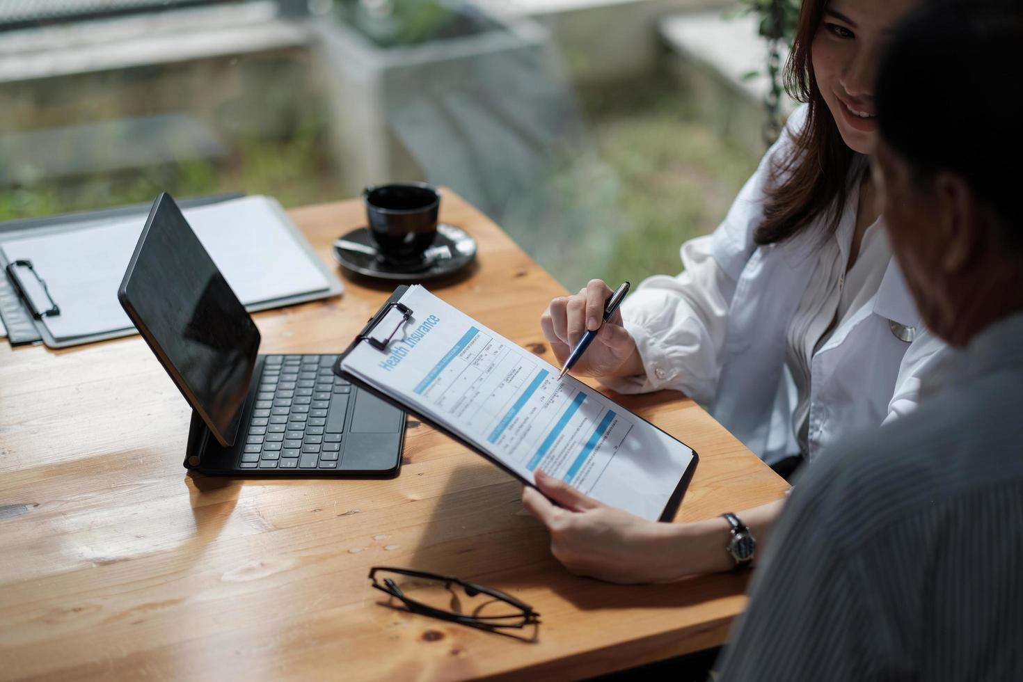 Female health insurance broker presenting his insurance benefits to businessman fill out insurance policy. To prevent future incidents. photo