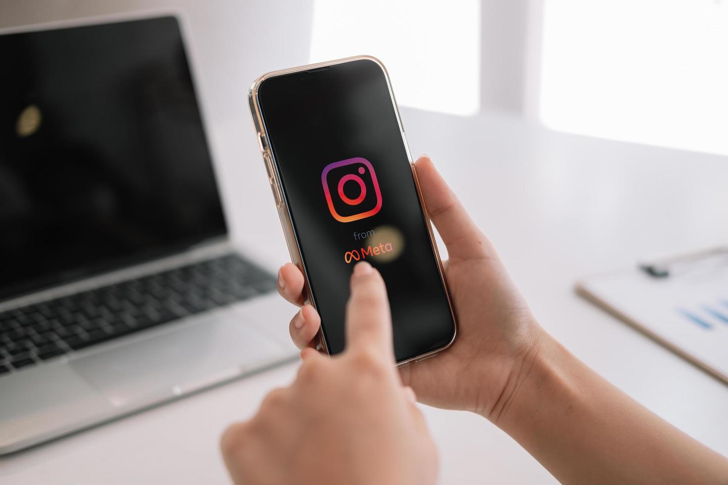 A woman holds Apple iPhone 13 with Instagram application from meta on the screen at cafe. Instagram is a photo-sharing app for smartphones photo