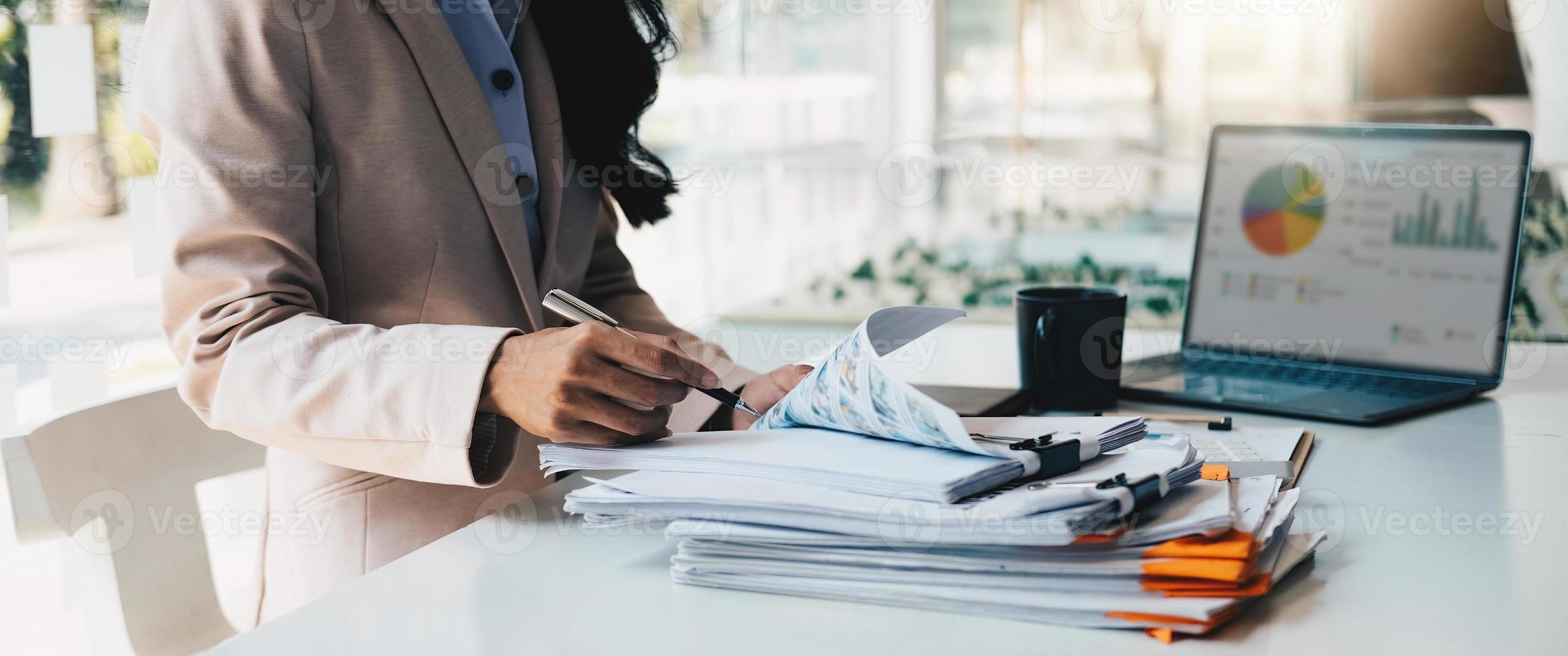 Accounting planning budget concept  Business woman offices working for arranging documents unfinished stack of document papers with pen photo