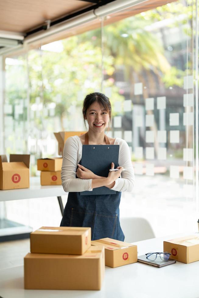 Portrait of Asian young woman SME working with a box at home the workplace.start-up small business owner, small business entrepreneur SME or freelance business online and delivery concept photo