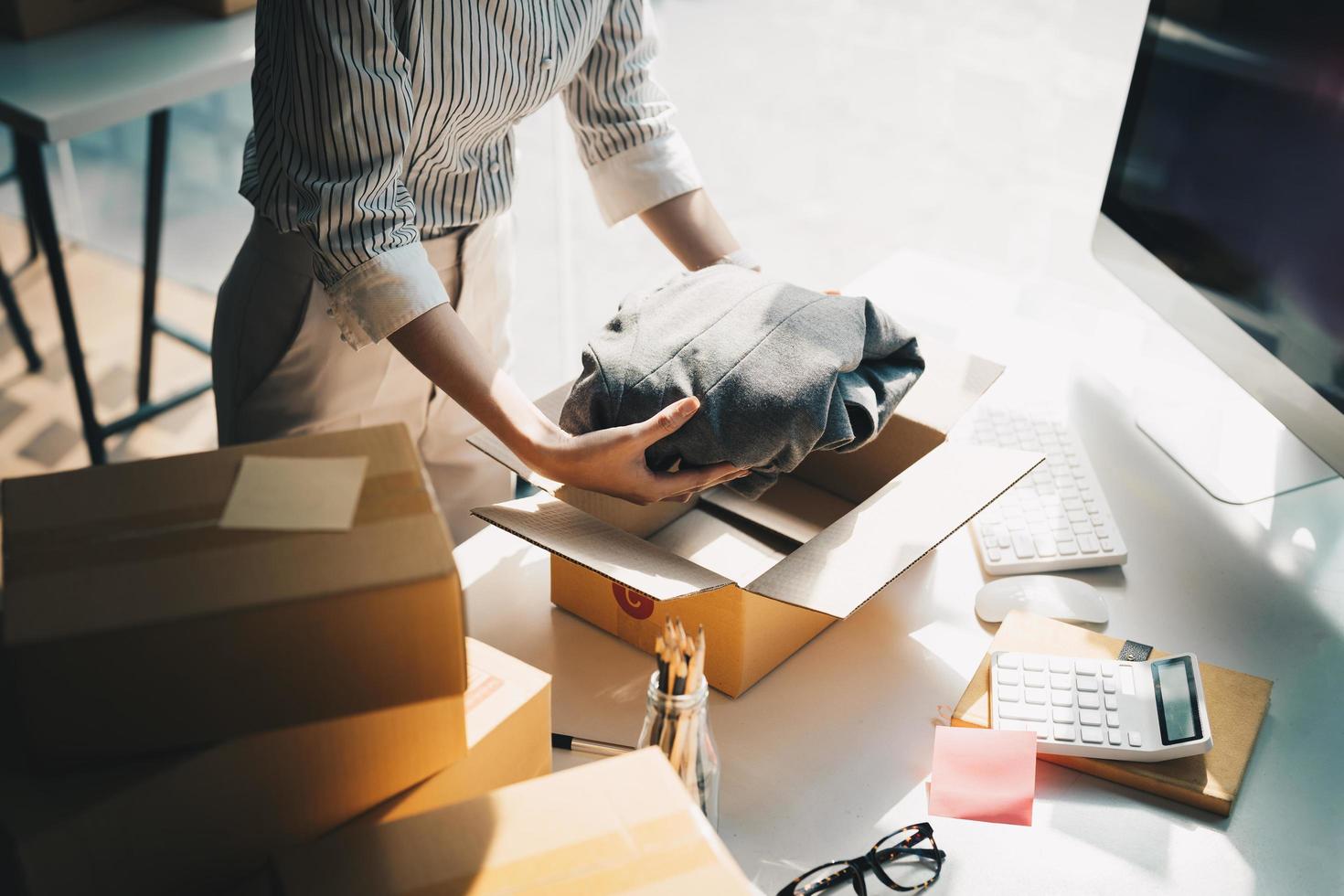 mujer independiente que trabaja con ropa de embalaje, empresaria nueva propietaria de una pequeña empresa en casa, concepto de embalaje y entrega de vendedor de negocios en línea foto