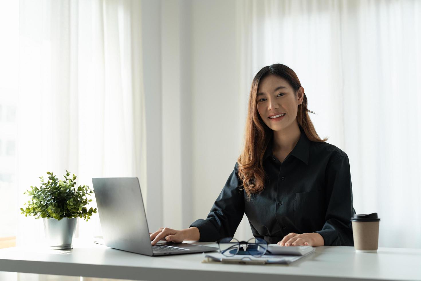 Attractive asian woman working about financial with business report and laptop computer. financial or accounting concept. photo