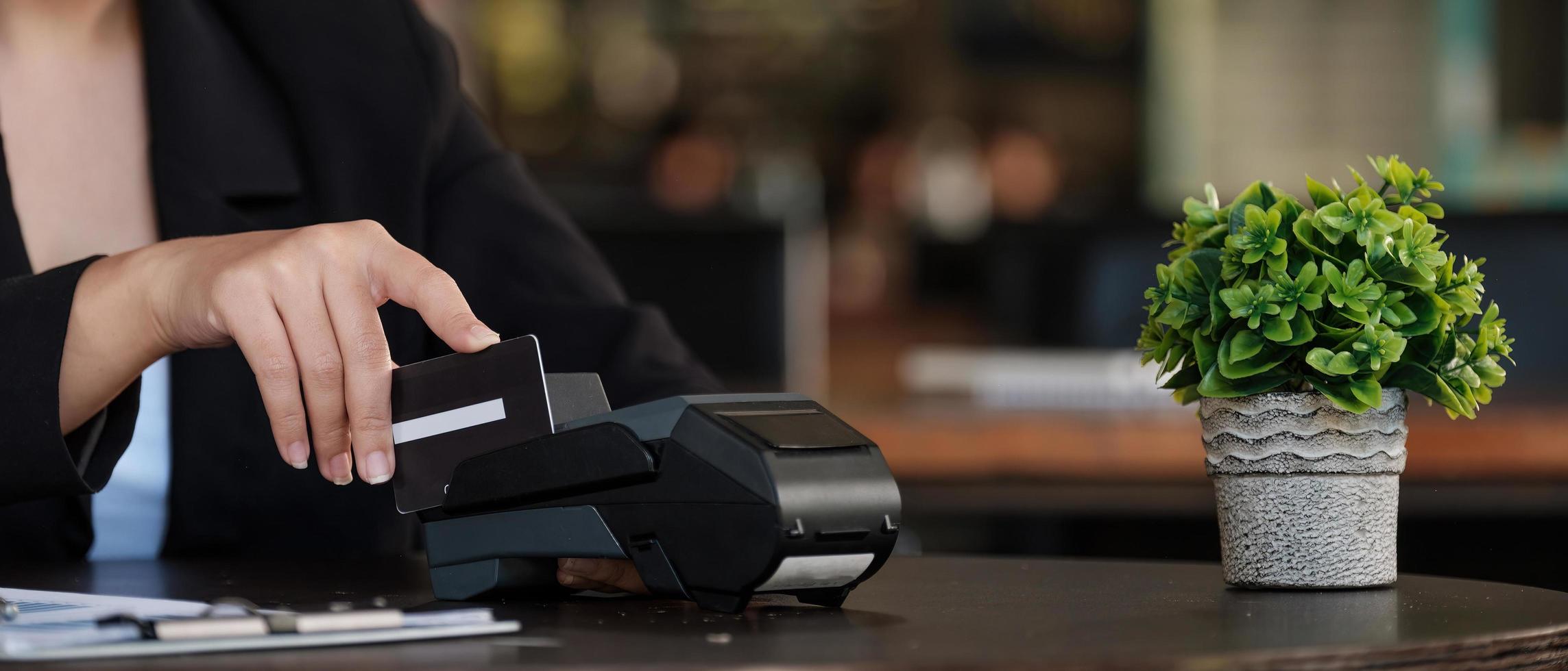 businesswoman hand pushing the button and swipe credit on terminal standing in shopping mall. shopping and retail concept photo